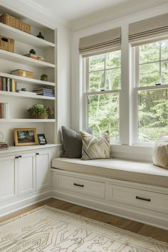 a window seat in front of two windows with bookshelves on both sides and a rug underneath it