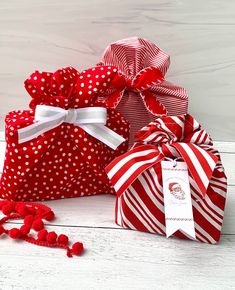 three red and white gift bags with polka dots on them, one has a bow