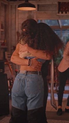 two women hug each other in the middle of a room with guitars on the wall