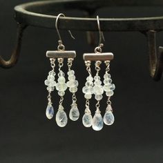 "Rainbow Moonstone Chandelier Earringsin Glowing moonstone briolettes wrapped carefully with Sterling Silver wire and dangling below Rainbow Moonstone beads stacked together. These are natural, excellent AAA quality gems. Each briolette is faceted beautifully and sparkle with every movement. Light, dangly, with shimmery stones these are an elegant and feminine, chic statement earrings, perfect for special occasion, wedding, holidays or as a Gift for Her. Mesurements: The earrings drop around 1.5 Wire-wrapped Moonstone Dangle Earrings, Moonstone Chandelier, Flower Earrings Gold, Silver Chandelier, Feminine Chic, Moonstone Beads, Green Gems, Earrings Drop, Earrings Sterling Silver