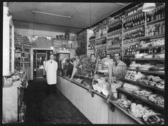 an old black and white photo of some people in a store with shelves full of food