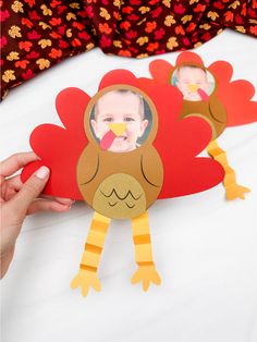 a person holding up a turkey cutout on top of a white table with red and orange flowers