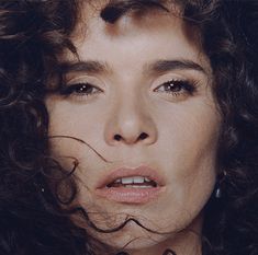 a close up of a person with curly hair and an unkempt look on her face