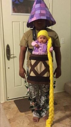 a man in a costume holding a baby wearing a hat and braids on his head