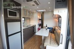 a kitchen and living room in an rv with wood flooring, white walls and cabinets