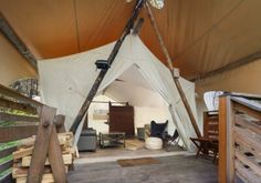 the inside of a large tent with wood and canvas on it's walls, in front of a wooden fence