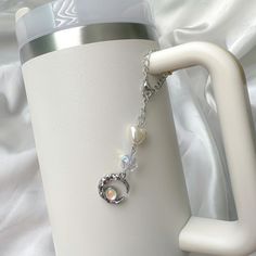 a close up of a cup with a chain attached to the handle and a heart charm on it