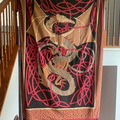 a red and black tapestry hanging on the side of a wooden stair case next to a banister