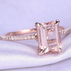 an engagement ring with a pink diamond in the center on top of a white cloth