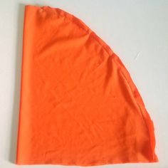 an orange piece of cloth is laying on the table with it's corner cut out