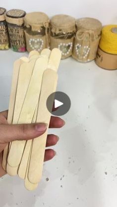 a person holding several wooden sticks in front of some rolls of thread and spools of twine