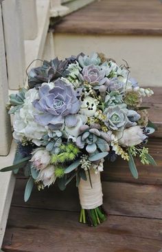 a bridal bouquet with succulents and greenery sits on the steps