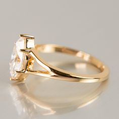 a yellow gold engagement ring with a square cut diamond in the center, on a white background