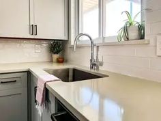 a clean kitchen with white cabinets and gray counter tops is seen in this image from the front view