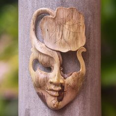 a carved wooden mask on the side of a pole