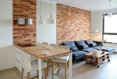 a living room filled with furniture and a wooden table in front of a brick wall