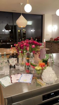 the kitchen counter is covered with bottles and glasses, flowers in vases, and cards