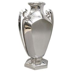 a large silver vase sitting on top of a metal stand in front of a white background