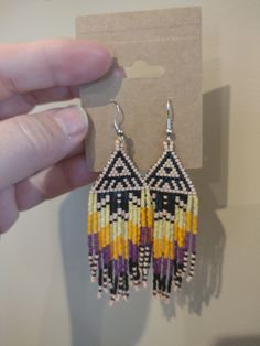 a pair of colorful beaded earrings is being held by a person's hand