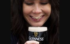 a woman holding a guinness glass in her right hand