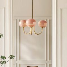 a dining room table and chairs in front of a white wall with pink lamps hanging from it