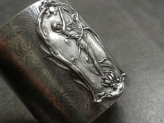 This wide silver cuff bracelet is Art Nouveau jewelry  that features an Art Nouveau muse dancing in the wind as the focal point.  The plaque is bolted securely to the silver plated brass cuff base, and curves around for a nice fit.     I have hand rolled  a design onto a plain cuff base, giving it an etched effect. This is one of the first pieces I have patterned with my new rolling mill, and I will be having fun designing other pieces with it. They have a nice oxidized finish, and great details.  It is 2.5 inches wide and will fit an average sized  wrist quite nicely. There is a silver leather backing to cover the bolts for comfort. Art Nouveau. Thanks for looking at my shop: serrelynda.etsy.com Here are my other bracelets: https://www.etsy.com/shop/Serrelynda?section_id=6106743&ref=shops Artistic Silver Cuff Bracelet, Artistic Silver Cuff Bracelet Bangle, Artistic Silver Cuff Bangle Bracelet, Artistic Silver Bangle Cuff Bracelet, Bijoux Art Nouveau, Bracelet Art, Rolling Mill, Nouveau Jewelry, Large Bracelet