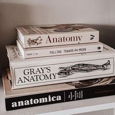 three books stacked on top of each other in front of a white wall and shelf