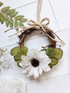 a wreath with white flowers and green leaves hanging on a wall next to other items