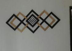 a decorative wall hanging on the side of a white wall with black and gold squares