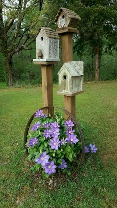 two bird houses are sitting on top of a planter with purple flowers in it