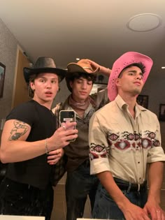 three young men standing next to each other in front of a mirror holding cell phones