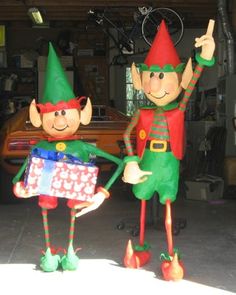 two inflatable garden gnomes holding gifts and giving them thumbs up to the camera