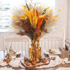 a vase filled with flowers sitting on top of a table next to plates and candles