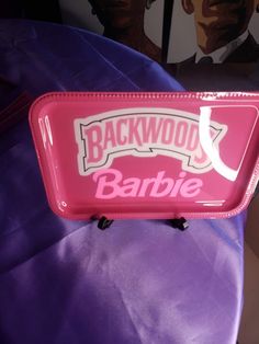 a pink tray with the name backwool's barbie on it sitting on a purple pillow