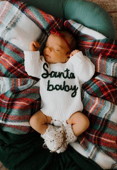 a baby wrapped in a blanket with the words santa body on it's chest