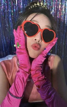 a woman wearing pink gloves and heart shaped sunglasses with her hands on her face, posing for the camera