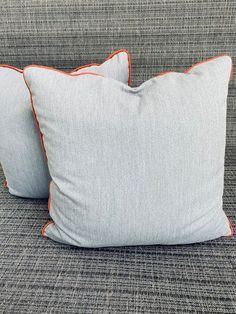 two blue and orange pillows sitting on top of a gray couch next to each other