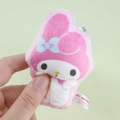 a hand holding a small hello kitty plush toy