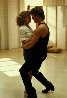 a man and woman are dancing in an empty room