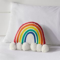 a rainbow pillow with pom poms on it and a white polka dot pillow