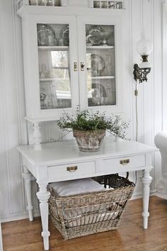 a white hutch with glass doors and baskets on it's sides in a living room