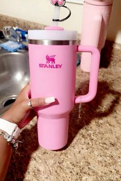 a woman is holding a pink travel mug