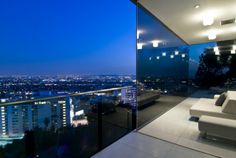 a living room filled with furniture next to a large window overlooking a city at night