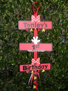 a birthday sign hanging from the side of a green bush in front of some bushes