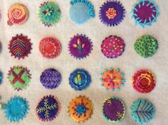 a bunch of different colored objects on a white table cloth with scissors and thread spools