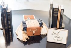 some books are sitting on a table next to a small box with a sign that says find your seat