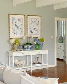 a living room filled with furniture and paintings on the wall above it's console table