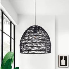 a large black rattan light hanging from a ceiling in a room with white walls