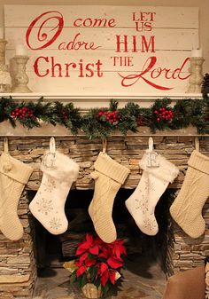 christmas stockings hanging from a mantel in front of a sign that says come to adore him christ the lord