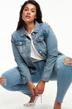 a woman in ripped jeans squatting down with her hand on her hip and looking at the camera